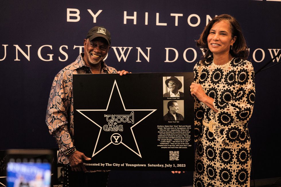 Robert "Kool" Bell and Tia Sinclair Bell, wife of Ronald Bell (deceased), holding the plaque. Photo Credit: Stephanie Sheronovich