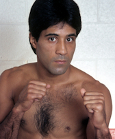 Portrait of Harry Arroyo, shirtless with bare fists raised.